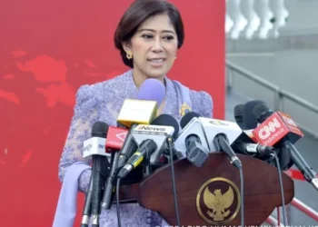 Menteri Komunikasi dan Digital Meutya Hafid berbicara di podium dengan beberapa mikrofon media di depannya