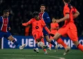 Pemain Barcelona berseragam oranye menendang bola saat dikelilingi pemain Paris Saint-Germain berseragam biru dalam pertandingan sepak bola.