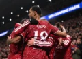 Sejumlah pemain Liverpool berseragam merah saling berpelukan merayakan gol di lapangan.