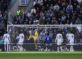 Kiper berseragam kuning melompat menghalau bola di depan gawang, dikelilingi pemain Chelsea berseragam putih dan Everton berbaju biru