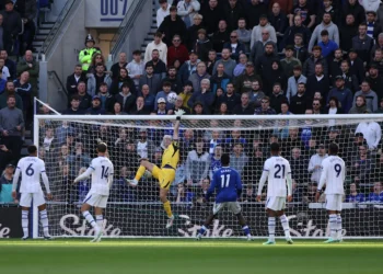 Kiper berseragam kuning melompat menghalau bola di depan gawang, dikelilingi pemain Chelsea berseragam putih dan Everton berbaju biru