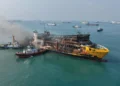KMP Batumandi dengan bekas kebakaran dan kapal pemadam di sekitarnya