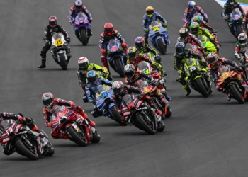 Sejumlah pembalap MotoGP melaju berkelompok melewati tikungan lintasan balap.