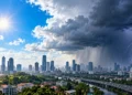 Ilustrasi pemandangan kota dengan langit cerah dan matahari di sisi kiri serta awan gelap, hujan deras, dan kilat di sisi kanan