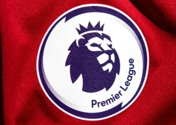 Logo Premier League bergambar kepala singa bermahkota pada permukaan kain merah.