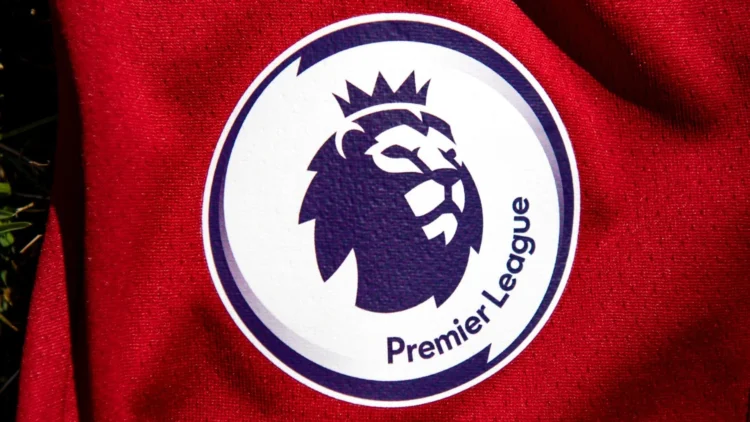 Logo Premier League bergambar kepala singa bermahkota pada permukaan kain merah.