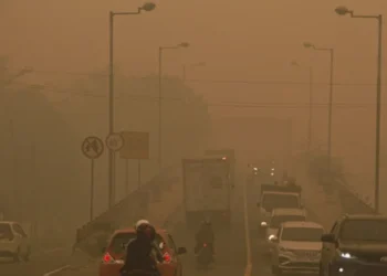 Sejumlah mobil dan sepeda motor melintasi jalan yang diselimuti kabut asap tebal dengan jarak pandang terbatas
