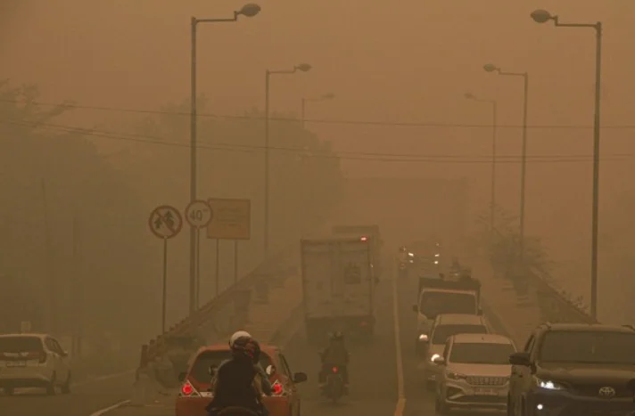 Sejumlah mobil dan sepeda motor melintasi jalan yang diselimuti kabut asap tebal dengan jarak pandang terbatas