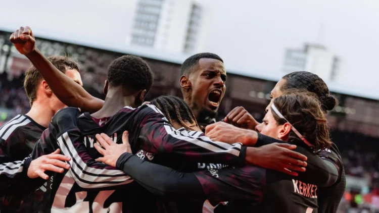 Sejumlah pemain Liverpool mengenakan seragam gelap saling merangkul di lapangan.