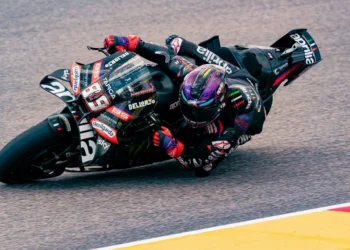 Pembalap mengendarai motor balap Aprilia berwarna gelap saat menikung di lintasan