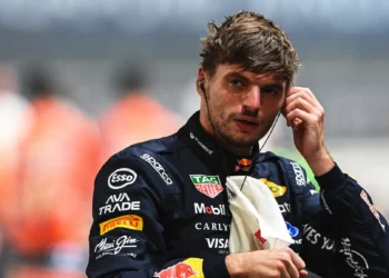 Max Verstappen mengenakan seragam balap Red Bull Racing sambil menyentuh alat komunikasi di telinganya