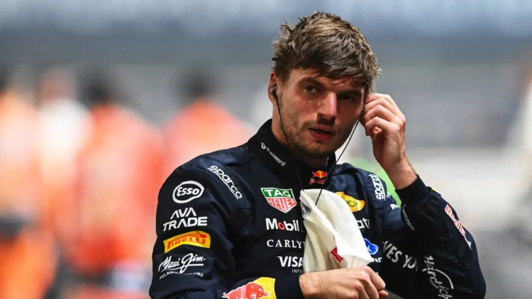 Max Verstappen mengenakan seragam balap Red Bull Racing sambil menyentuh alat komunikasi di telinganya