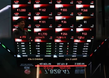 Papan elektronik menampilkan angka harga saham berwarna merah dan hijau di area perdagangan
