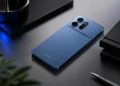 Bagian belakang ponsel berlogo Samsung berwarna biru dengan tiga kamera yang diletakkan di atas meja