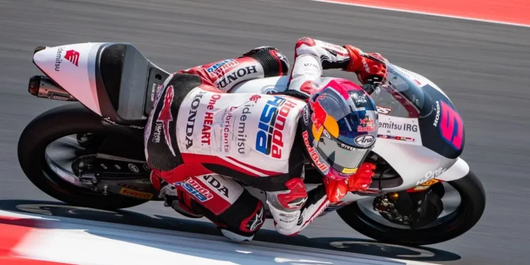 Veda Ega Pratama menunggangi motor balap Honda Team Asia bernomor 9 sambil menikung di lintasan