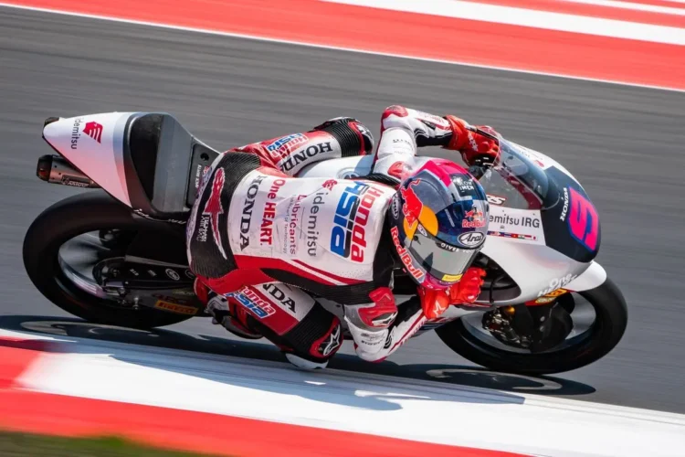 Veda Ega Pratama menunggangi motor balap Honda Team Asia bernomor 9 sambil menikung di lintasan