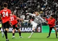 Pemain Juventus berseragam hitam putih berusaha menjangkau bola di antara pemain Rennes berseragam merah di lapangan.