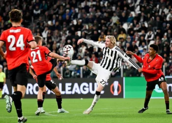 Pemain Juventus berseragam hitam putih berusaha menjangkau bola di antara pemain Rennes berseragam merah di lapangan.
