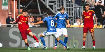Pemain AS Roma berbaju merah dan pemain Como berseragam biru berebut bola di lapangan