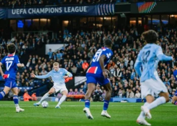 Pemain Manchester City berseragam biru muda melepaskan tembakan di antara pemain Paris Saint-Germain berseragam biru tua di lapangan