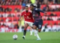 Seorang pemain Manchester United berbaju merah mengejar pemain Tottenham berbaju biru tua nomor 13 yang berlari menuju bola