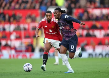 Seorang pemain Manchester United berbaju merah mengejar pemain Tottenham berbaju biru tua nomor 13 yang berlari menuju bola