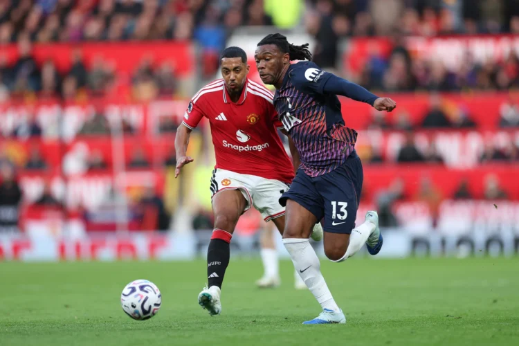 Seorang pemain Manchester United berbaju merah mengejar pemain Tottenham berbaju biru tua nomor 13 yang berlari menuju bola