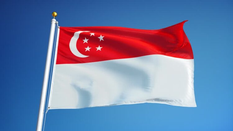 Bendera Singapura berwarna merah putih dengan bulan sabit dan lima bintang berkibar di langit biru