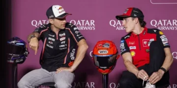 Jorge Martin dengan pakaian tim Aprilia dan Marc Marquez dengan pakaian tim Ducati duduk berbincang dengan dua helm di antara mereka