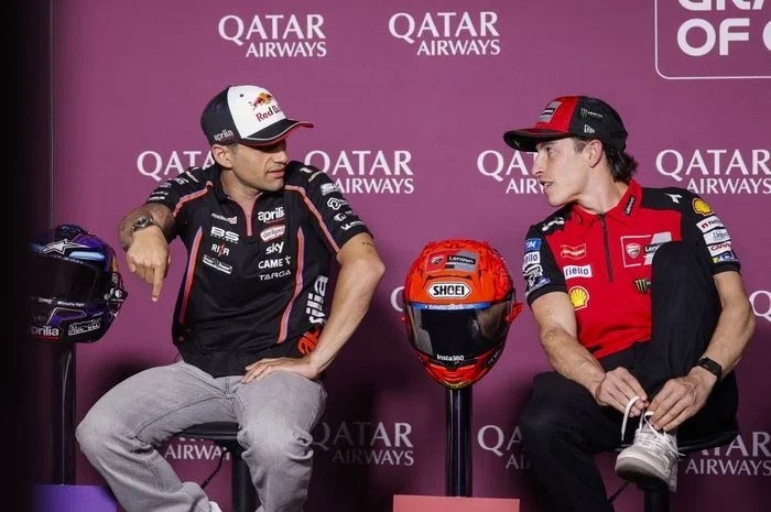 Jorge Martin dengan pakaian tim Aprilia dan Marc Marquez dengan pakaian tim Ducati duduk berbincang dengan dua helm di antara mereka