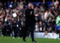 Michael Carrick mengenakan setelan hitam dan bertepuk tangan di tepi lapangan