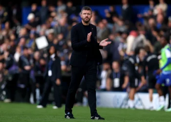 Michael Carrick mengenakan setelan hitam dan bertepuk tangan di tepi lapangan