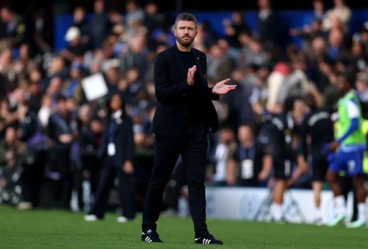 Michael Carrick mengenakan setelan hitam dan bertepuk tangan di tepi lapangan