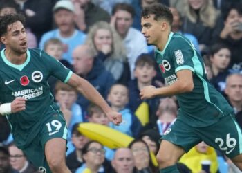 Dua pemain Brighton mengenakan seragam hijau tua merayakan gol di depan pendukung pada pertandingan melawan Manchester City
