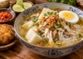Semangkuk Soto Banjar dengan kuah bening keemasan, ayam suwir, ketupat, soun, telur rebus, dan bawang goreng